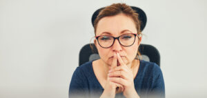 A woman with glasses with her forefingers to her lips to help illustrate Do I Qualify for Weight Loss Surgery Quiz