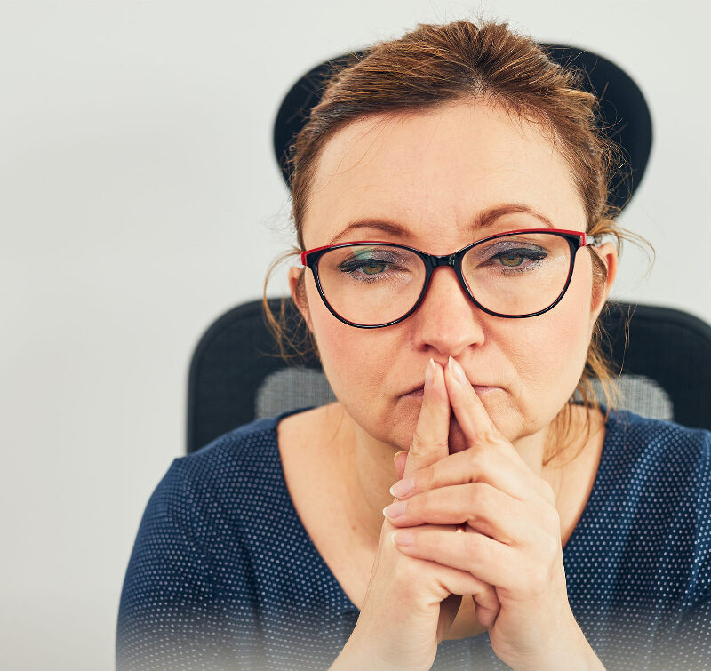 A woman with glasses with her forefingers to her lips to help illustrate Do I Qualify for Weight Loss Surgery Quiz